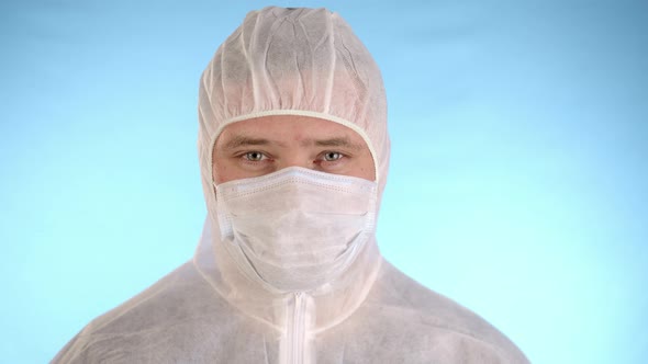 Man in protective jumpsuit removes medical mask, hood, sighs deeply and smiling