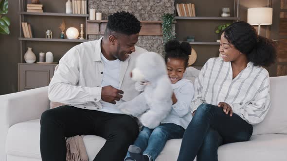 African Happy Family Parents with Child Daughter Sitting on Sofa at Home Having Fun Sincerely alt
