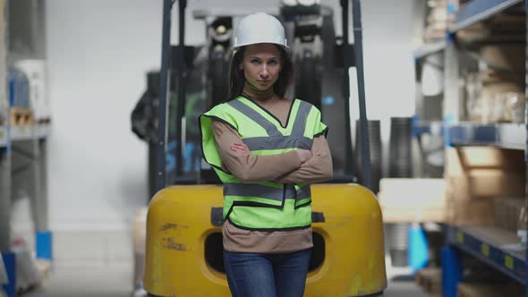 Gorgeous Slim Caucasian Woman Standing at Forklift Crossing Hands Looking at Camera with Serious alt