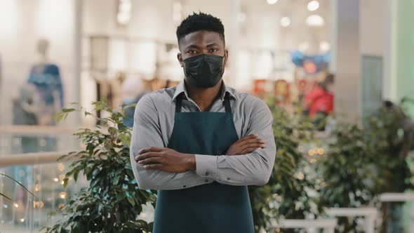 Confident African American Man Wearing Medical Mask Standing Indoors Looking at Camera Young Waiter alt