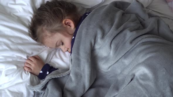 Authentic Cute Little Girl Sleeping Sweetly In Comfortable White and Grey Bed Middle Plan alt