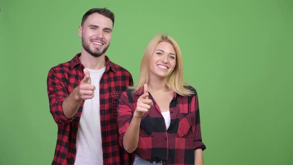 Young Happy Couple Pointing to Camera Together