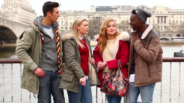 Multiracial group of friends in London looking at a smart phone alt