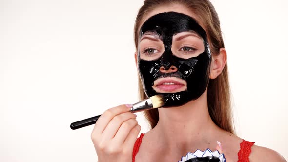 Girl Applying Black Mask to Face alt