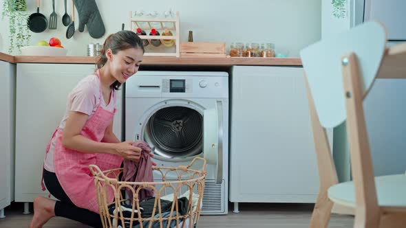 Asian beautiful woman doing laundry housework, put dirty clothes to washing machine in house. alt