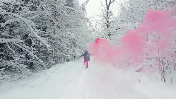 Woman in Pink Clothes Scarf and Hat Runs with Colored Smoke in Her Hands alt
