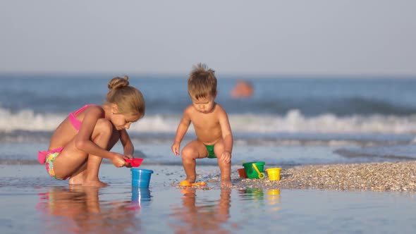 Older Sister Playing with Younger Brother Aground Near the Shore on Summer Vacation alt