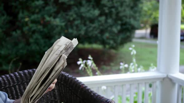 Senior man reading newspaper and drinking lemonade outdoors alt