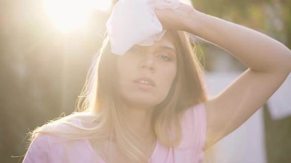 Closeup Exhausted Young Housewife in Sunbeam Rubbing Forehead Looking at Camera alt