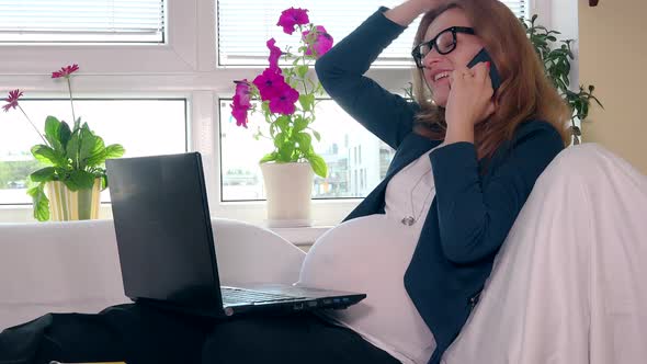 Happy Pregnant Caucasian Woman Working from Her Home While Sitting on White Bed