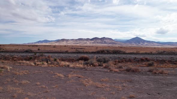 Low drone shoting to the right of a railroad track in the desert alt