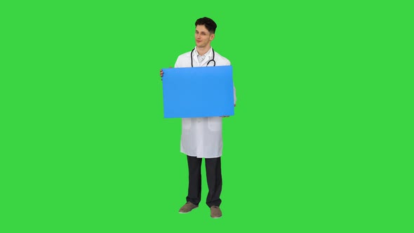 Smiling Male Doctor Wearing a Stethoscope Holding Blank Poster on a Green Screen, Chroma Key. alt