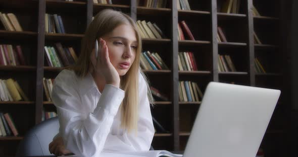 Business Woman in a White Shirt Works at a Laptop and Takes Notes alt