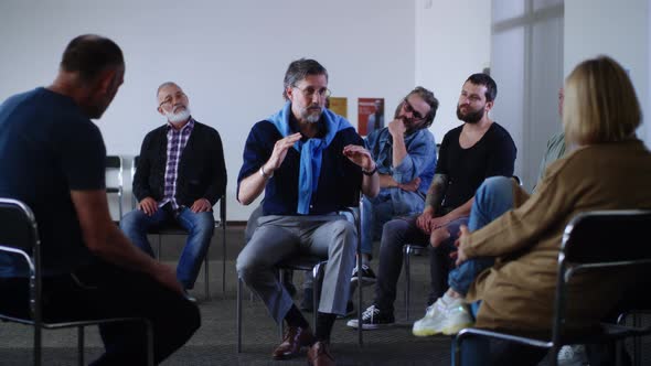 Male Counselor Speaking with Woman During Group Meeting alt