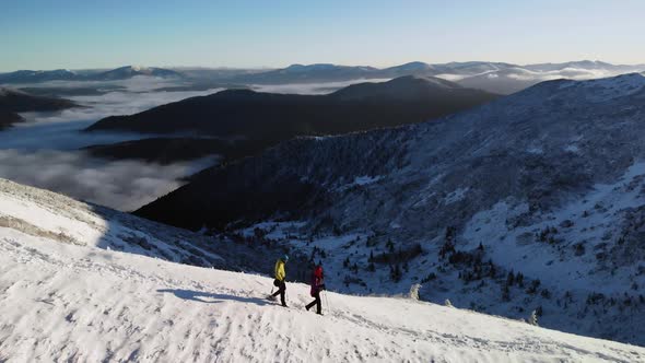 Two Hikers Walking on Snowy Mountain Ridge