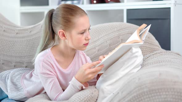 Adorable Focused Pupil Child Girl Confidently Reading Book Turning Paper Page Relaxing at Home alt