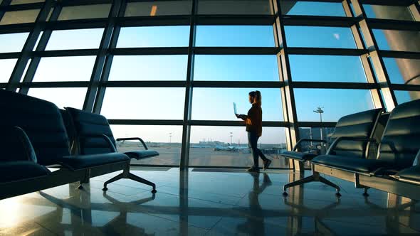 Woman Is Working on a Laptop in the Departure Lounge alt