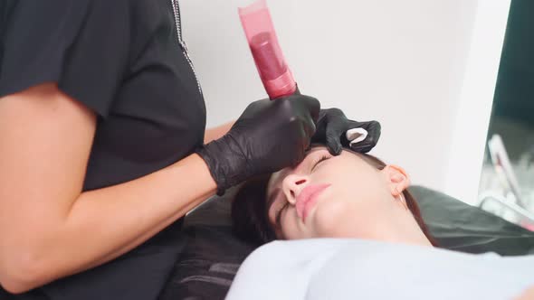 Master Makes Permanent Eyebrow Makeup Procedure to Woman in Beauty Salon alt