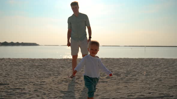 Toddler Runs Across the Sand Near the Ocean to the Camera Smiling and Waving alt