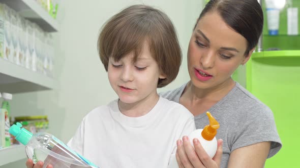 Beautiful Woman and Her Son Choosing Between Two Products at Drugstore alt