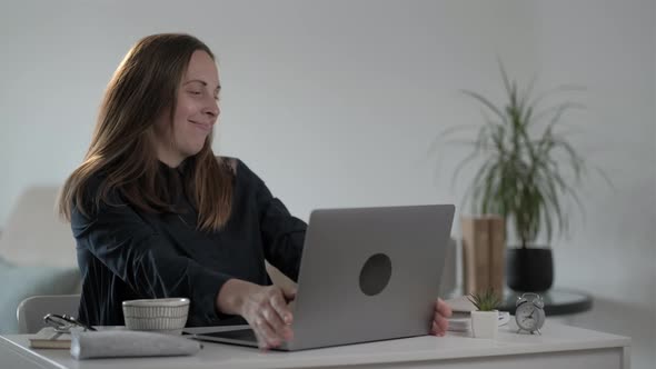 Smiling young woman freelancer using laptop computer and  typing message alt