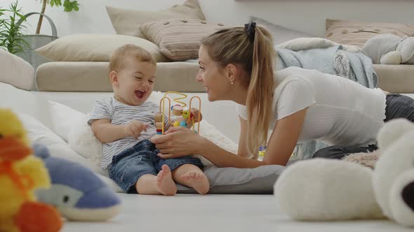 Happy and smiling mom with baby playing in living room at home