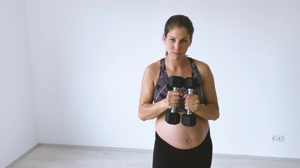 Slow motion shot of pregnant woman during exercise with dumbbells