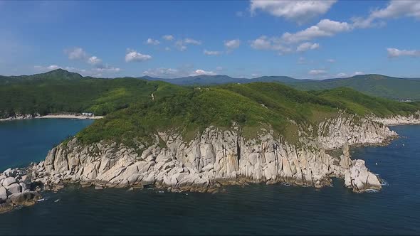 Aerial Shot Moving Along the Coastline of Deep Blue Sea Along a Dramatic Cliff Edge on Sunny Day alt