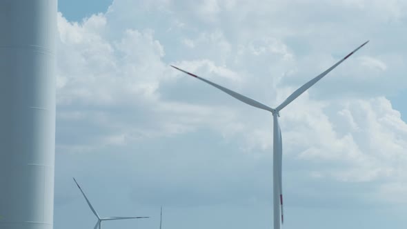 Wind Turbines Generate Electricity Against Fluffy Clouds