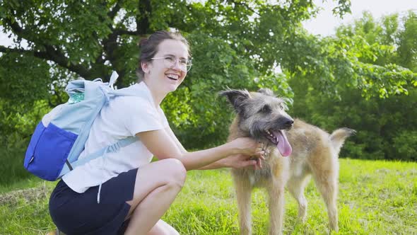 Woman with Backpack Leashes Dog in Park