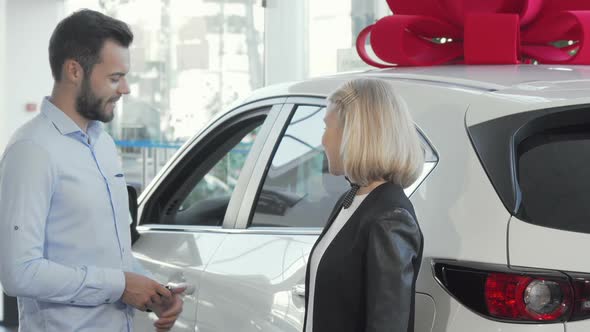 Woman Smiling To the Camera While Her Husband Examining Inside of a New Car