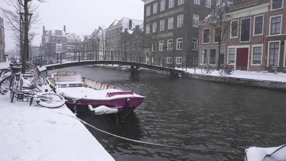 Rhine river flowing through snowy Leiden city centre, winter Netherlands city alt