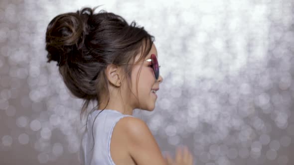 Cute Happy Little Girl Child in a Silver Dress Dancing on Background of Silver Bokeh