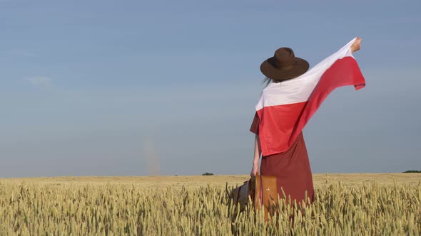 Girl with Poland flag and suitcase in wheat field with blue sky on background