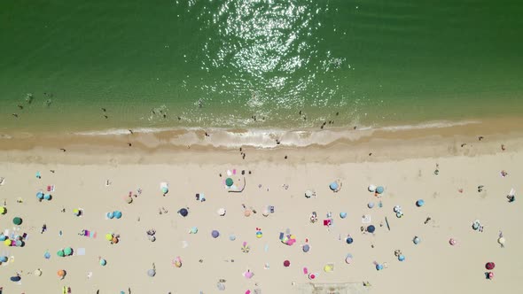 Colourful parasols and people relaxing at the beach in Sesimbra, Portugal alt