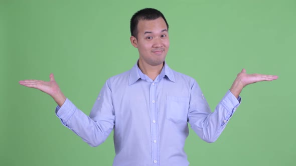 Happy Asian Businessman Comparing Something alt