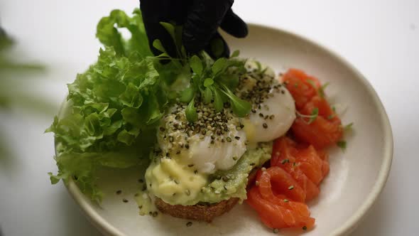 Cook Garnishes Guacamole and Poached Eggs Toast with Greenery alt