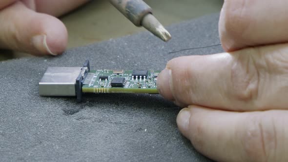 Manual soldering of electronic components on a PCB board, close up alt