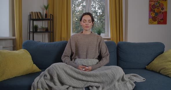 Young Woman Meditating at Home with Closed Eyes Indoors Slow Motion. Front View of Attractive Girl