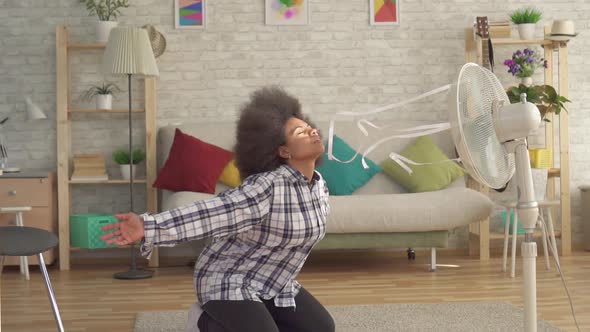 African Woman with an Afro Hairstyle in Front of the Fan Is Saved From Heat Slow Mo alt