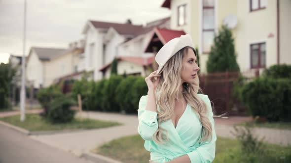 Portrait of Beautiful Woman in Long Mint Dress Keeps the Hat Away From the Wind