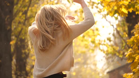 Fall outdoor. Fashionable lovable blonde woman dance laughing in autumn park. Beautiful Carefree gir