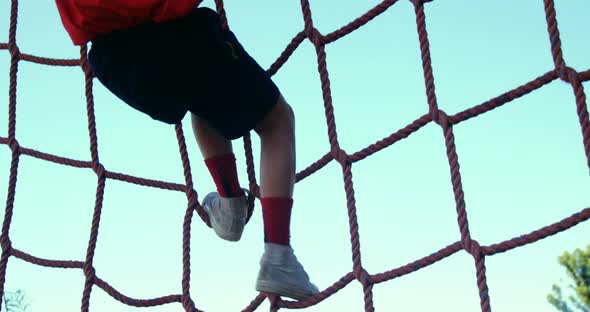 Boy climbing a net during obstacle course training alt