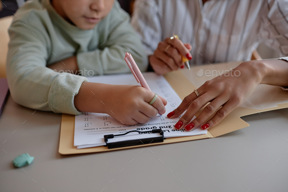 Little black girl doing math test at home with mother of tutor helping
