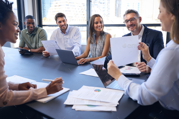 Multi-Cultural Business Team Meeting Around Office Boardroom Table With ...