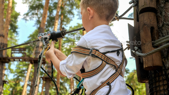 Closeup of little boy clamping safety rope with hook before riding on zip  line. Active childhood Stock Photo by kryzhov
