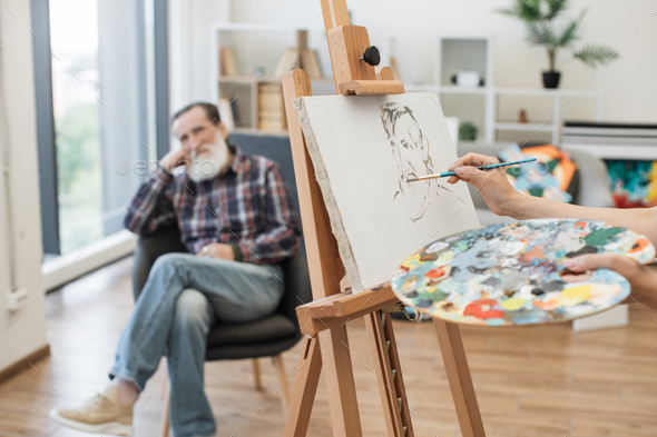 Lady making face contour of older man on canvas in workshop