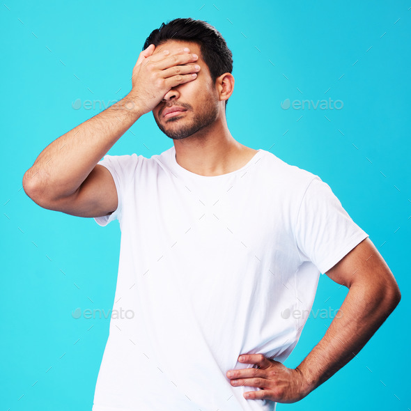 Man, face palm and mistake in studio with thinking, regret or anxiety for fail by blue background.