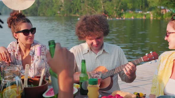 Joyous Man Playing Ukulele at Summer Party with Friends alt