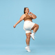 Young, positive, smiling overweight woman sportswear doing cardio exercises on blue background - PhotoDune Item for Sale